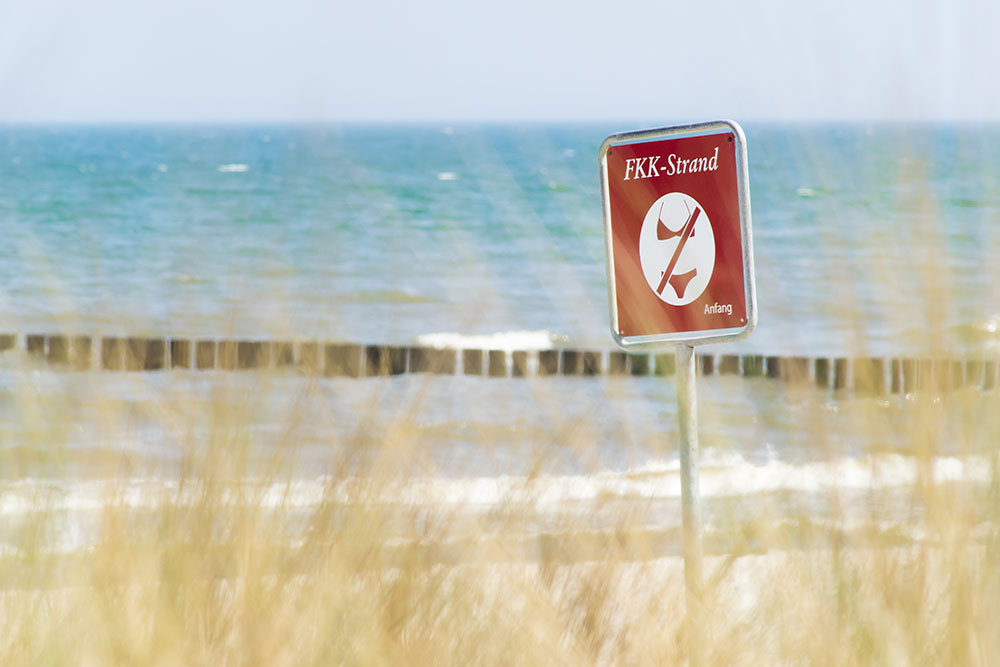 Schild für FKK an einem Strand, Badebekleidung verboten