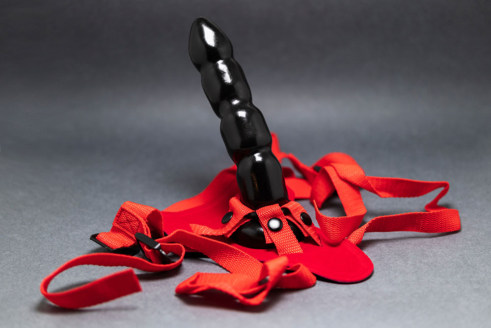 Schwarzer Strap-On mit roten Gurten