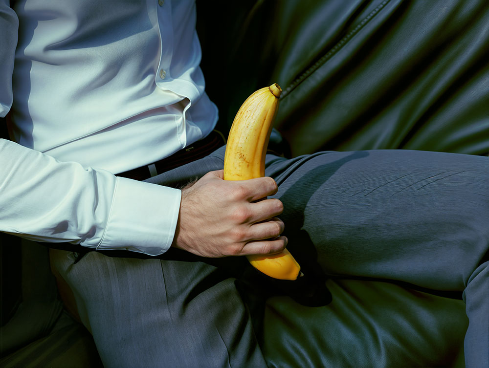 Mann in Anzug und Banane in der Hand als Zeichen der Masturbation - Michael