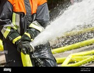 wasser-das-aus-einem-feuerwehrschlauch-spritzt-der-von-einem-feuerwehrmann-gehalten-wird-2ppnc58.jpg